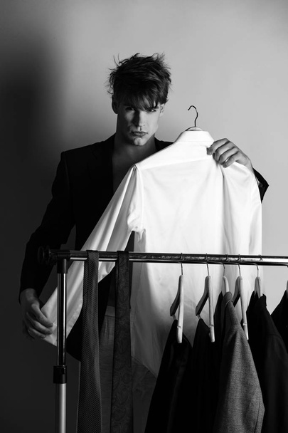 shirt in hand of happy man near wardrobe, shopping hanger - Foto, imagen