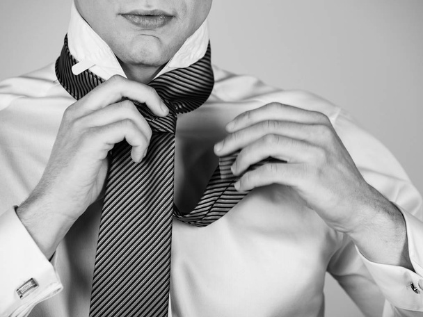 Man tying a striped tie in white shirt - Foto, afbeelding
