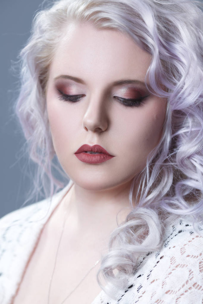 Beauty portrait of an elegant blonde with silvery curls isolated on a gray background. - 写真・画像