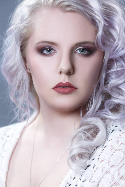 Beauty portrait of an elegant blonde with silvery curls isolated on a gray background. - Zdjęcie, obraz
