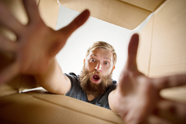 Man unpacking and opening carton box and looking inside - Photo, Image