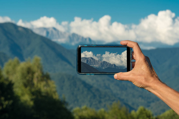 Käsin tekeminen valokuva älypuhelin kamera lähikuva, tarkastella turisti kädet käyttäen gadget puhelin matkustaa taustalla vuoret ja maisema
. - Valokuva, kuva