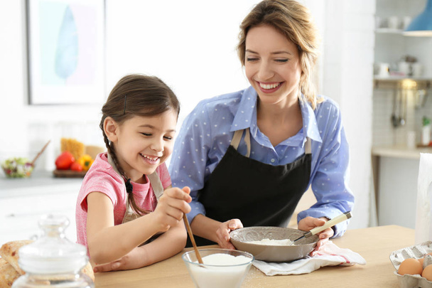 Young nanny with cute little girl cooking together in kitchen - Foto, Bild