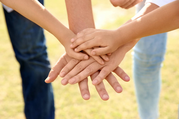 Vanhemmat ja heidän lapsensa laittaa kädet yhteen ulkona, lähikuva. Perhesiteet
 - Valokuva, kuva
