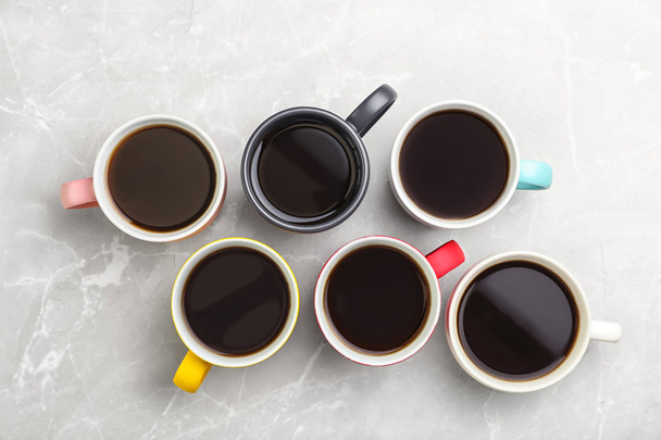 Many ceramic cups with hot aromatic coffee on marble background, flat lay - Photo, Image