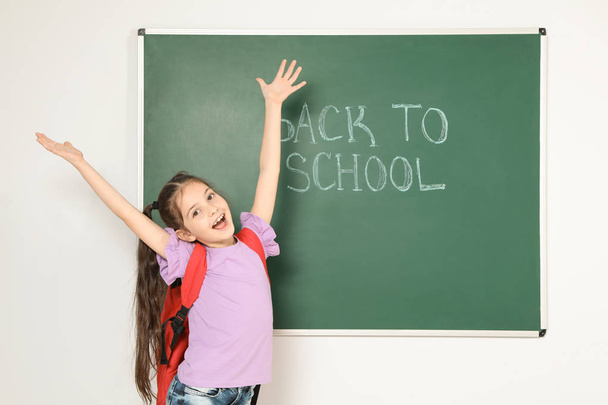 Little child near chalkboard with text BACK TO SCHOOL - Фото, изображение