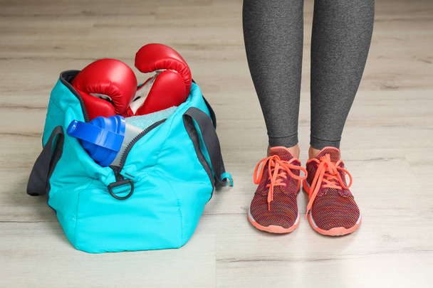 Young woman in sportswear and bag with gym equipment indoors - Foto, Bild