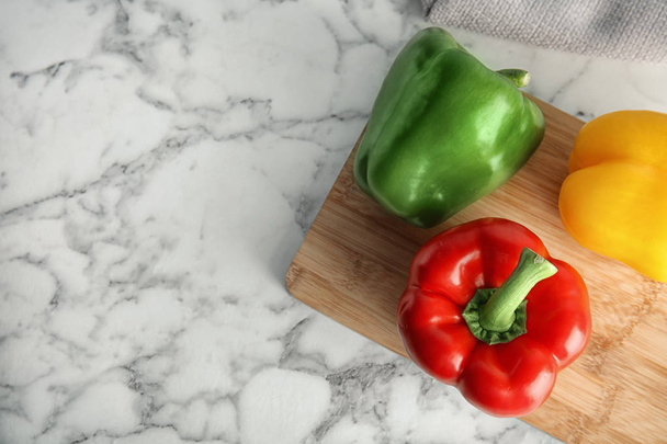 Wooden board with ripe paprika peppers on marble background, top view - Foto, Imagen