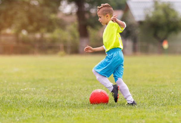 Chico pateando fútbol en el campo de deportes durante el partido de fútbol
 - Foto, Imagen
