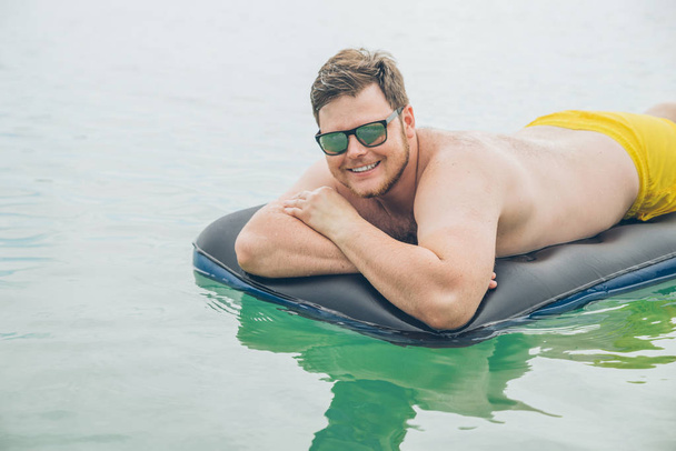 muž plavání na matraci v moři. letní čas koncept - Fotografie, Obrázek