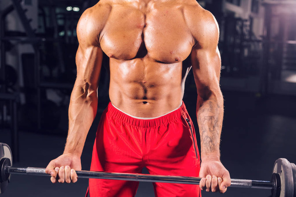 Izmos, fiatal férfi súlyemelés edzőteremben közelről - Fotó, kép