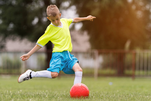 Chico pateando fútbol en el campo de deportes durante el partido de fútbol
 - Foto, imagen