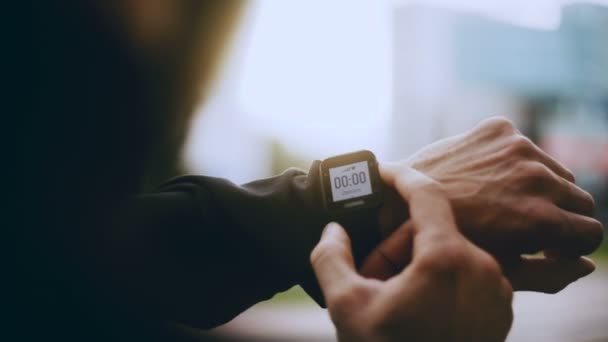 4K Sportsman usando relógio inteligente temporizador antes de começar. Homem olhando para um smartwatch temporizador rastreador para definir o tempo de execução
. - Filmagem, Vídeo