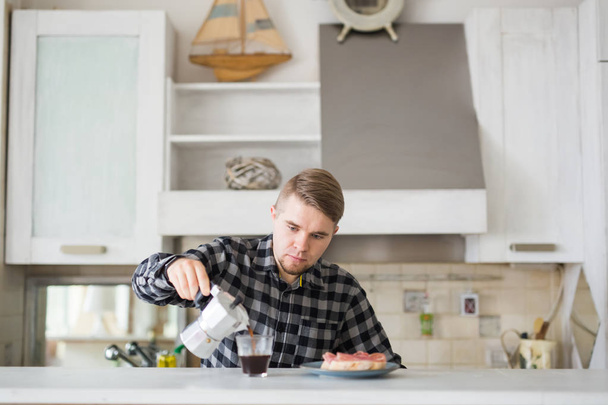 Conceito de manhã, bebida e pessoas - Retrato de homem bonito derramando café em uma caneca de café na cozinha
 - Foto, Imagem