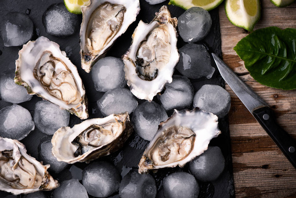 Oysters on stone black plate with ice and lemon - Foto, Bild