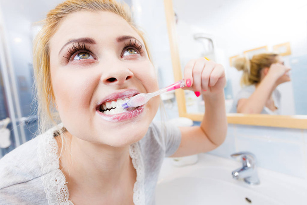 Woman brushing cleaning teeth closeup. Funny blonde girl with toothbrush in bathroom. Oral hygiene. Unusual wide angle view - Photo, Image