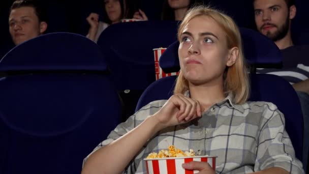 Atrakcyjna kobieta jedzenie popcorn na premierze filmu w kinie - Materiał filmowy, wideo