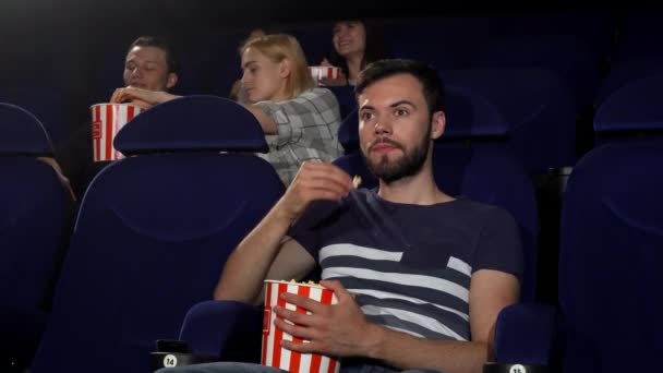 Χαρούμενος νεαρός άνδρας που δείχνει τους αντίχειρες επάνω ενώ παρακολουθείτε ταινίες στον κινηματογράφο - Πλάνα, βίντεο