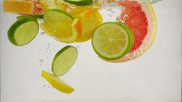 Darab citrusfélék lime, citrom, narancs, grapefruit esnek a vízbe, és fröccsenő buborékok, lassú mozgás közelről - Felvétel, videó