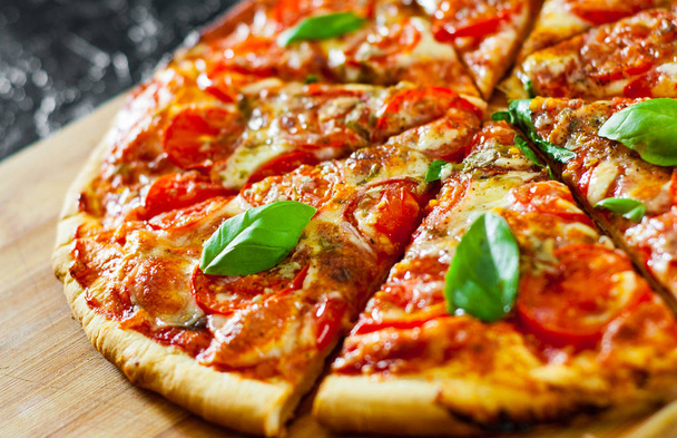 sliced Pizza with Mozzarella cheese, Tomatoes, pepper, Spices and Fresh Basil. Italian pizza. Pizza Margherita or Margarita - Zdjęcie, obraz