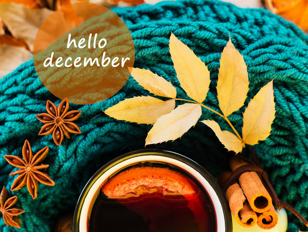 Winter, fall leaves, hot steaming cup of glint wine and a warm blue scarf on wooden table background. Seasonal, winter hot wine, Winter relaxing and still life concept. Text hello december - Photo, Image