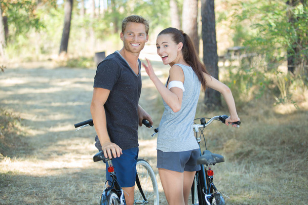 pareja feliz con bicicleta en un parque de la ciudad
 - Foto, imagen