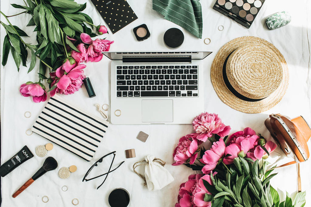 Flat lay, vista superior mulheres moda escritório mesa espaço de trabalho com flores de peônia, laptop, cosméticos, acessórios sobre fundo branco
. - Foto, Imagem