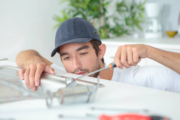 young plumber fitting a sink - Photo, image