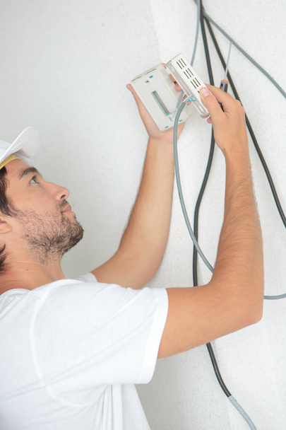 electrician fitting a thermostat system - Photo, image