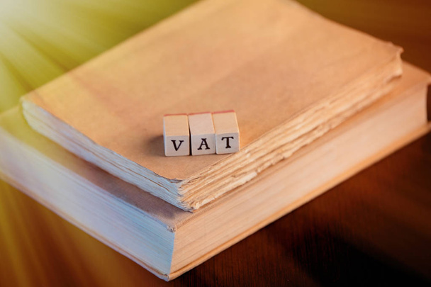 Word VAT and books on wooden table. Above view - Photo, Image