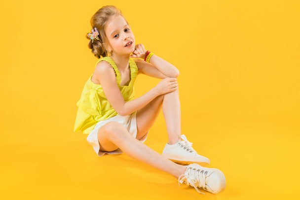 Una adolescente está sentada sobre un fondo amarillo
. - Foto, Imagen