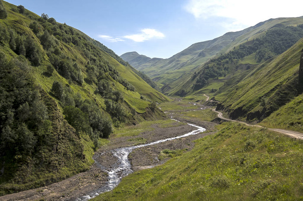Vuoristojoki kuljettaa vetensä tyynesti vihreässä laaksossa vuorten välissä - Valokuva, kuva