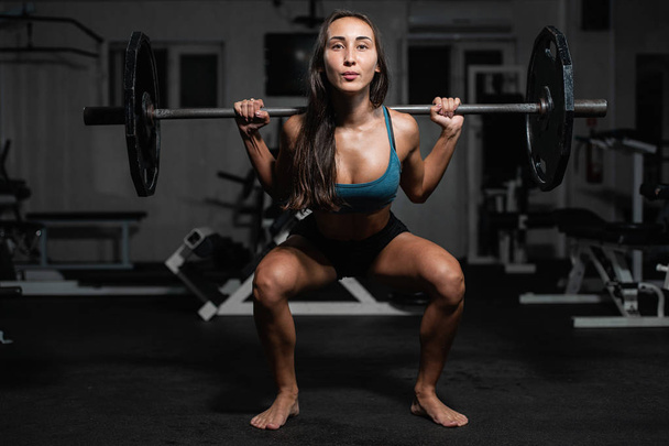 Handsome weightlifter lifting barbells with Squats. Female training with barbell, pumping legs - Foto, Imagen
