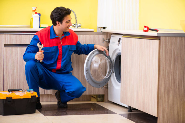 Reparador reparando máquina de lavar roupa na cozinha - Foto, Imagem