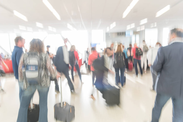 Blurred diverse group of passengers with luggage waiting in line at airport boarding gate in USA. Blurry group of travelers queuing to onboard to jet bridge airplane, final boarding gate - Photo, Image