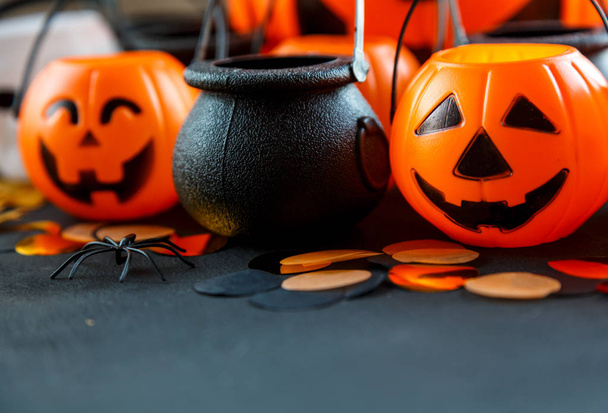 Halloween decorations. Decorative orange pumpkins, cauldrons, skulls on black background. Halloween concept.  - Foto, Imagen