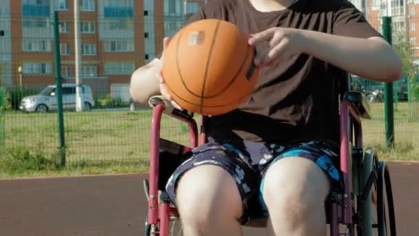 Gehandicapte man speelt basketbal van zijn rolstoel, op de open lucht - Video