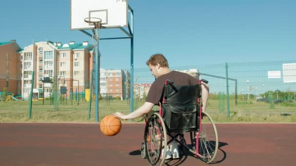 Людина з обмеженими можливостями грає в баскетбол зі свого інвалідного візка, на відкритому повітрі
 - Кадри, відео