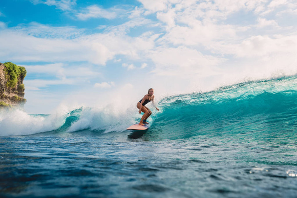 Mooie surfer vrouw op surfplank in Oceaan op blauwe hemelachtergrond  - Foto, afbeelding