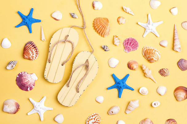 Decorative sandshoes,  seashells and starfish on yellow background. Vacation background, top view. - Fotografie, Obrázek