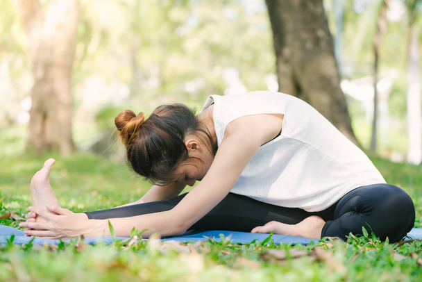 Jeune femme asiatique yoga en plein air garder le calme et médite tout en pratiquant le yoga pour explorer la paix intérieure. Yoga et méditation ont de bons avantages pour la santé. Yoga Sport et mode de vie sain concept
. - Photo, image
