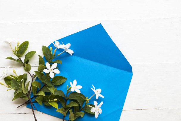 jasmin fleur blanche d'asie thailand arrangement en enveloppe bleue sur fond blanc en bois
 - Photo, image