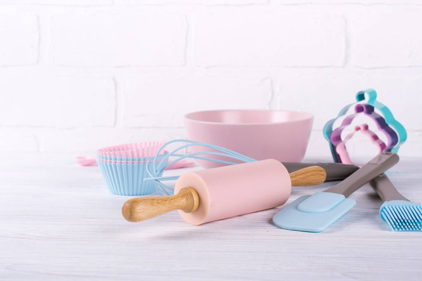 Baking background with kitchen tools: rolling pin, wooden spoons, whisk, sieve, bakeware and shape cookie cutter on white wooden background. - Photo, Image