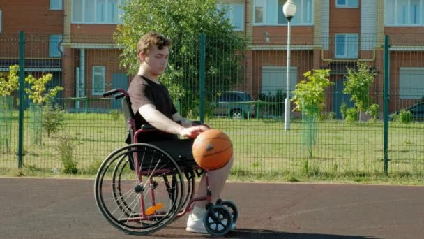 Behinderter spielt Basketball im Rollstuhl unter freiem Himmel - Filmmaterial, Video