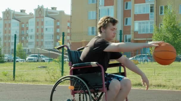 El hombre discapacitado juega baloncesto desde su silla de ruedas, al aire libre
 - Metraje, vídeo