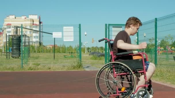 Niepełnosprawny mężczyzna gra w koszykówkę z wózku, na wolnym powietrzu - Materiał filmowy, wideo
