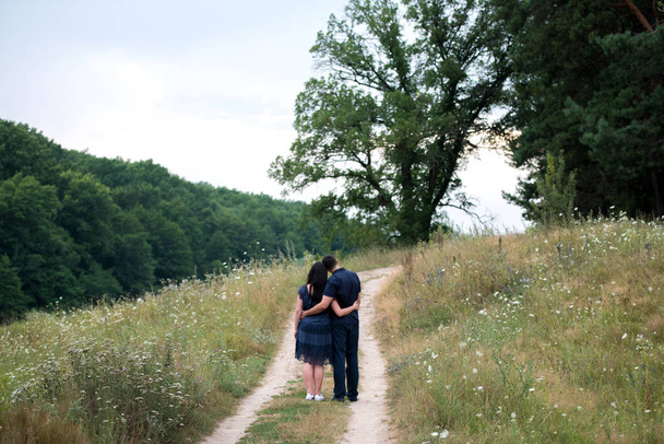 Couple in love embracing and walking outdoors near the forest, back view. Free space - Foto, Imagen