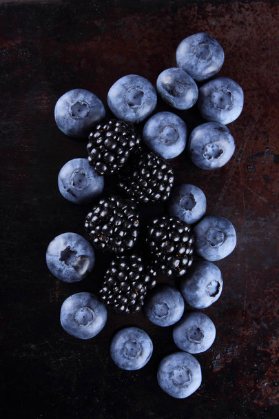 Blueberries and blackberries on a dark background, fresh berries for a vegan, fruits on a rusty background, assorted berry breakfast, copy space - Foto, Bild