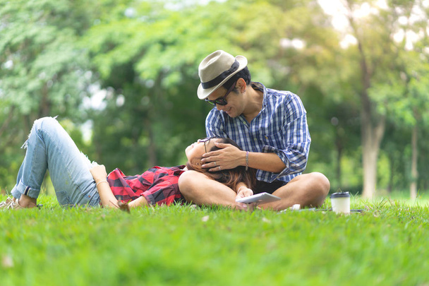 полная длина счастливой женщины, лежащей на коленях счастливого мужчины в парке
 - Фото, изображение