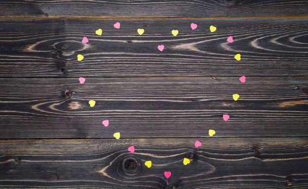 Pink and yellow heart sprinkles on wood background, copy space, text. Flat lay, top view. Valentines day background. Love concept. Holiday greeting card. Heart shaped frame made from colored sprinkles - Fotoğraf, Görsel